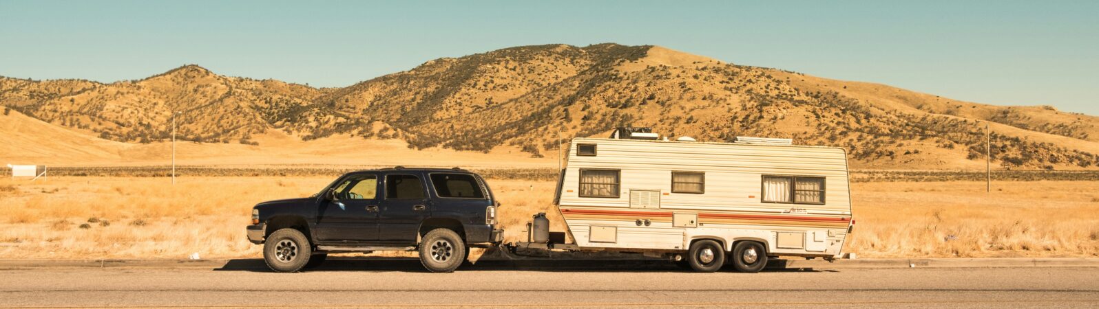 4x4 towing a caravan with mountains and blue sky in the background